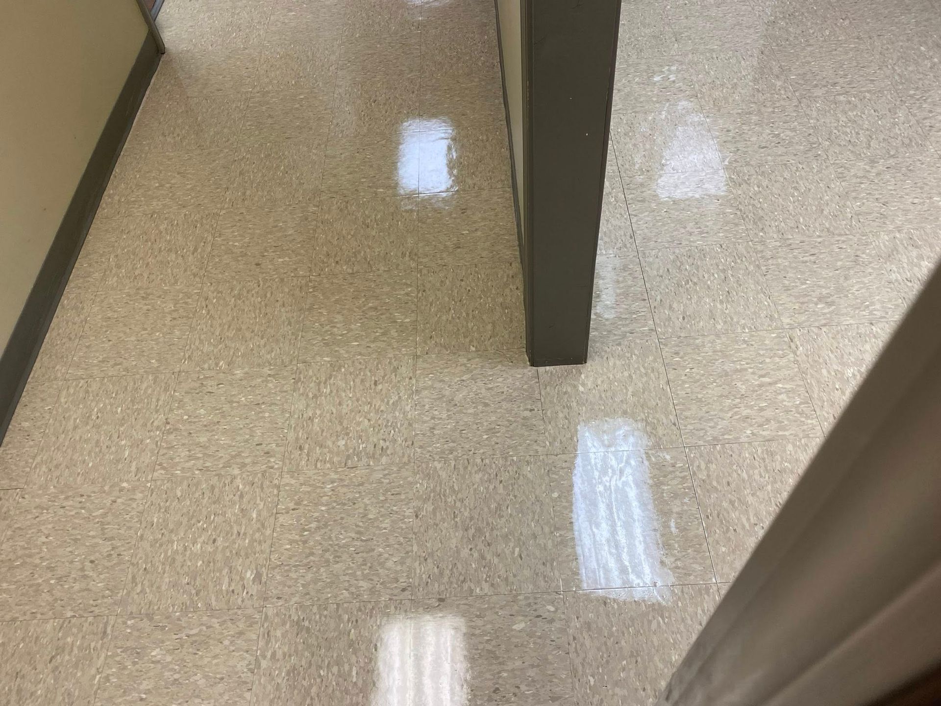 Beige speckled flooring with four rectangular patches of white on it.
