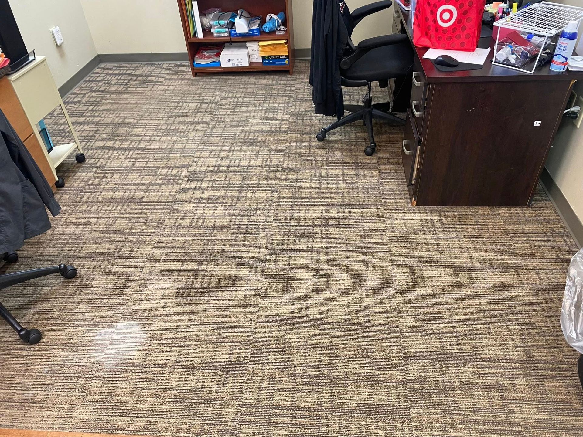 Office floor with patterned carpet, desk, shelves, and office chair.