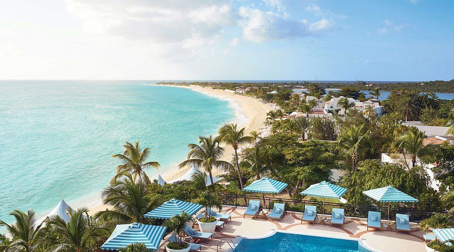 Oceanfront resort with turquoise water, sandy beach, and swimming pool.