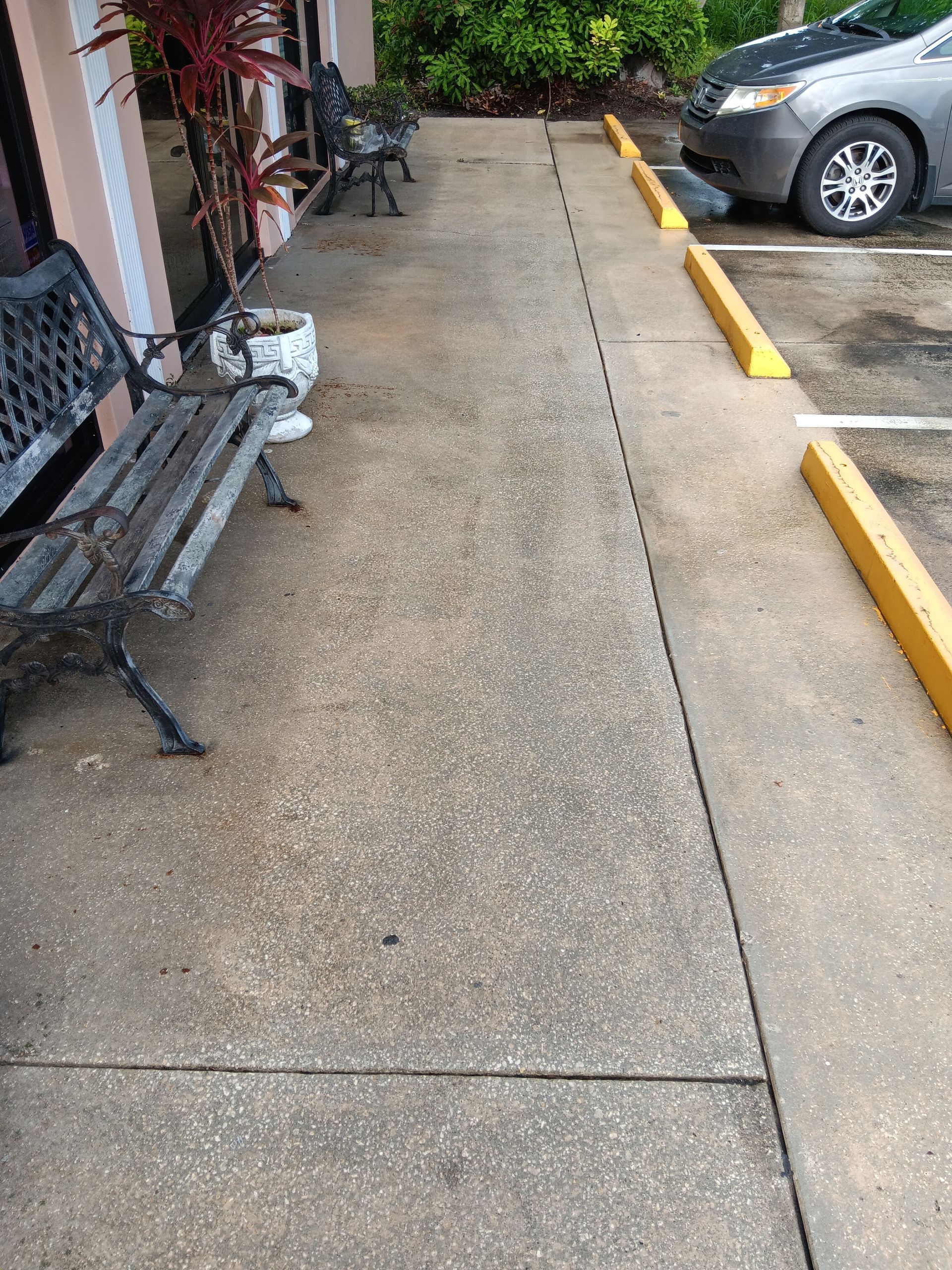 A bench is sitting on a sidewalk next to a parking lot