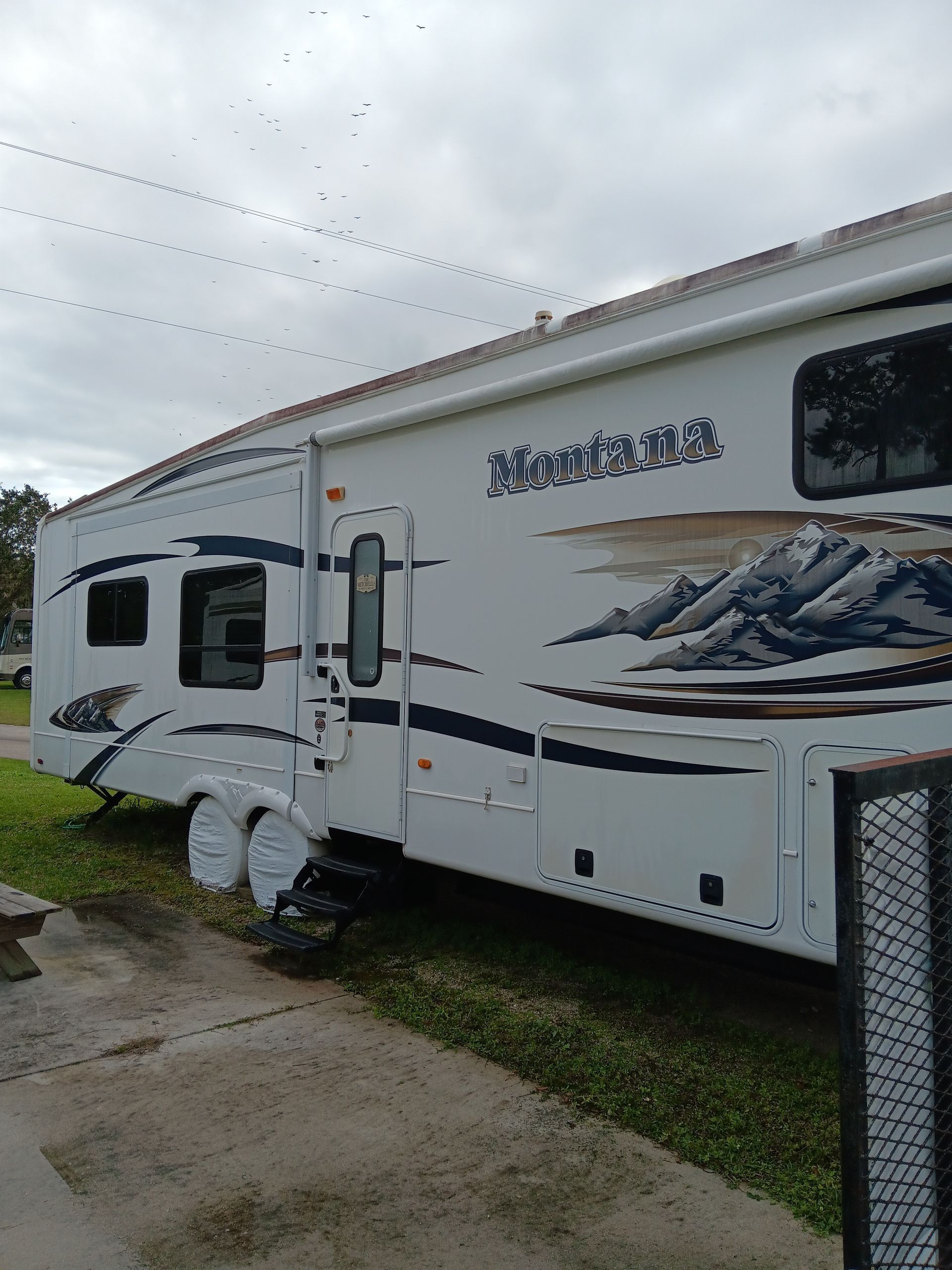 A white RV is parked in front of a house
