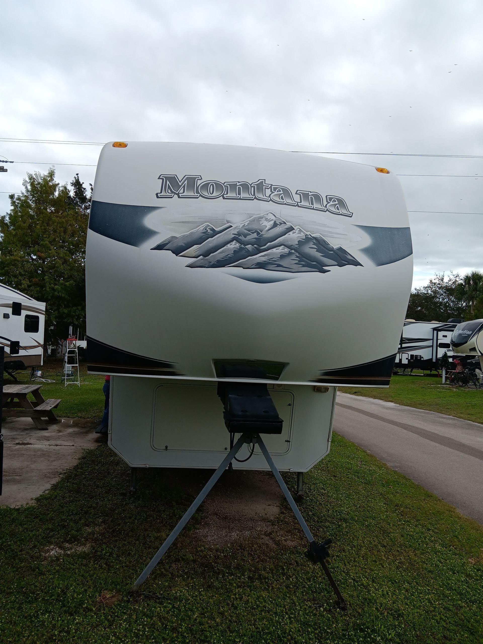 A white RV is parked in a grassy area next to a road