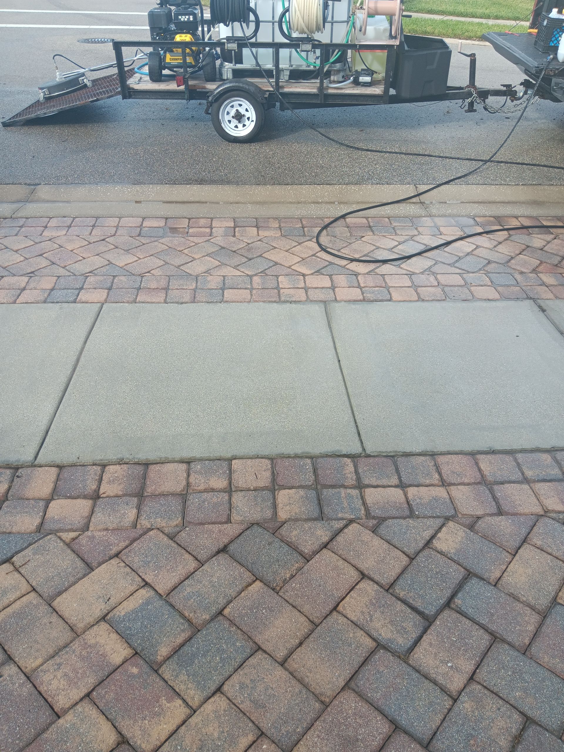 A trailer is parked on the side of the road next to a brick sidewalk