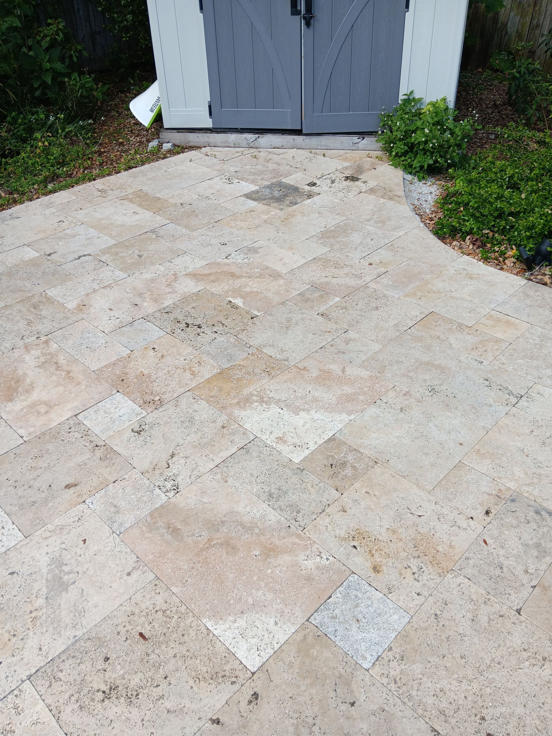 A stone walkway leading to a shed with a gray door