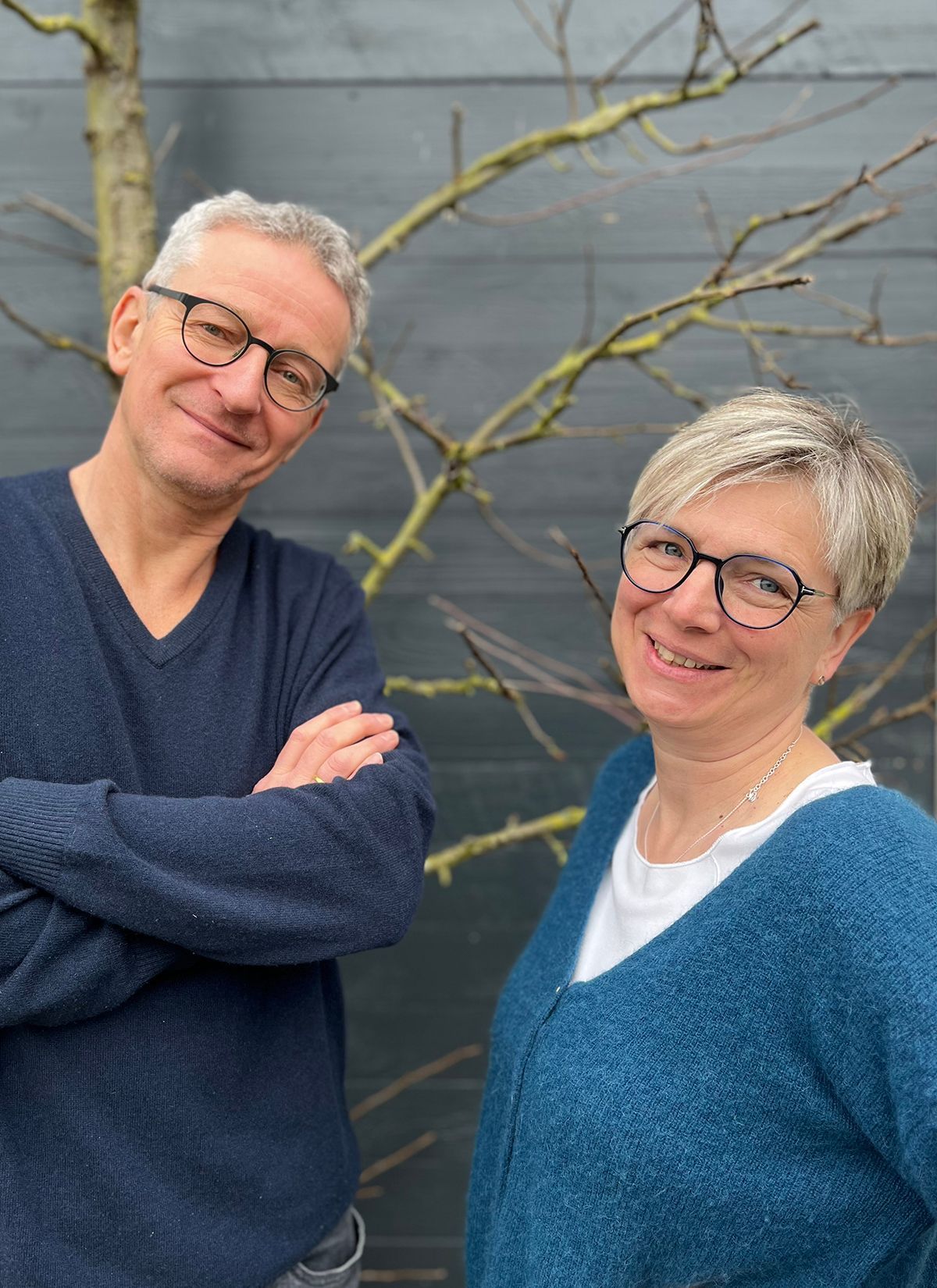Ein Mann und eine Frau stehen mit verschränkten Armen nebeneinander.