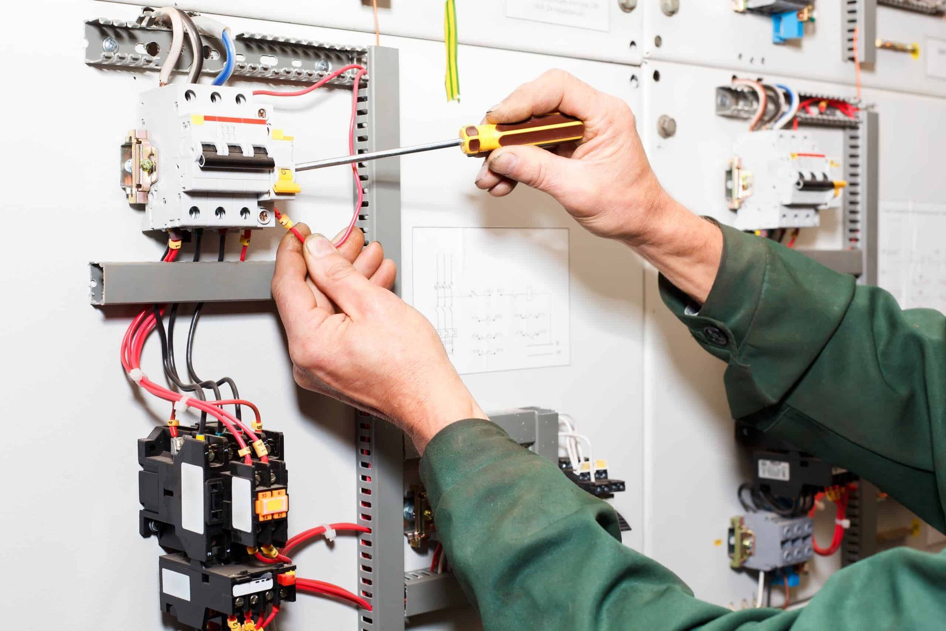 A Man is Working on an Electrical Panel With a Screwdriver — Refrigerated Technologies (QLD) Pty Ltd In Collinsville, QLD