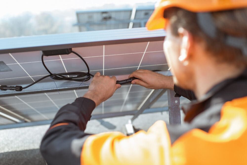 A Man is Installing a Solar Panel on a Roof — Refrigerated Technologies (QLD) Pty Ltd In Bowen, QLD