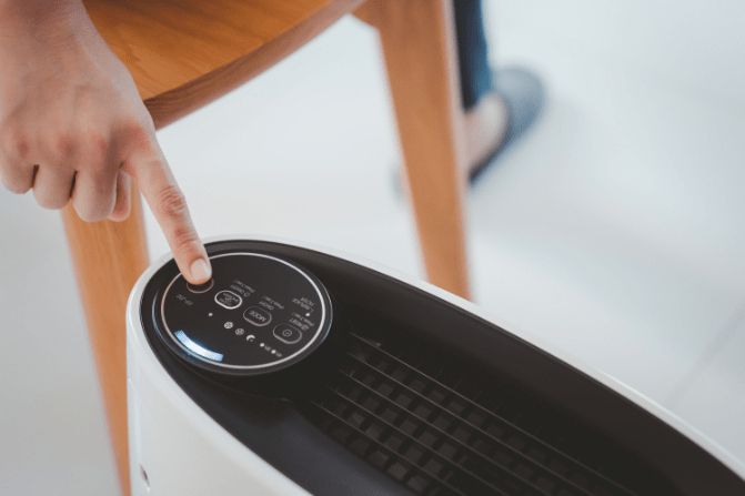 A Person is Pressing a Button on a Air Conditioner — Refrigerated Technologies (QLD) Pty Ltd In Airlie Beach, QLD