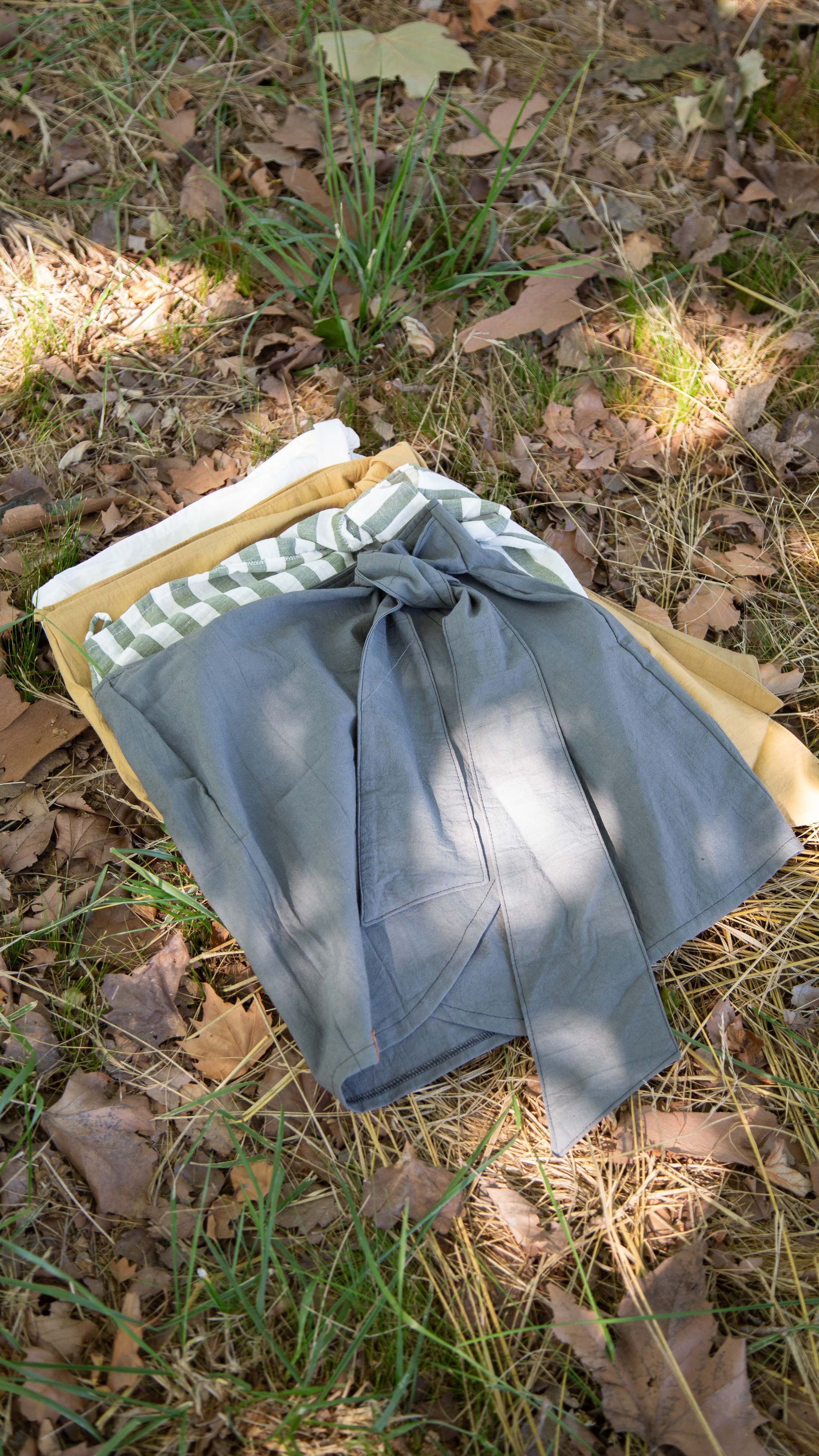 Mujer con camiseta blanca y falda cruzada de rayas verdes, al aire libre.