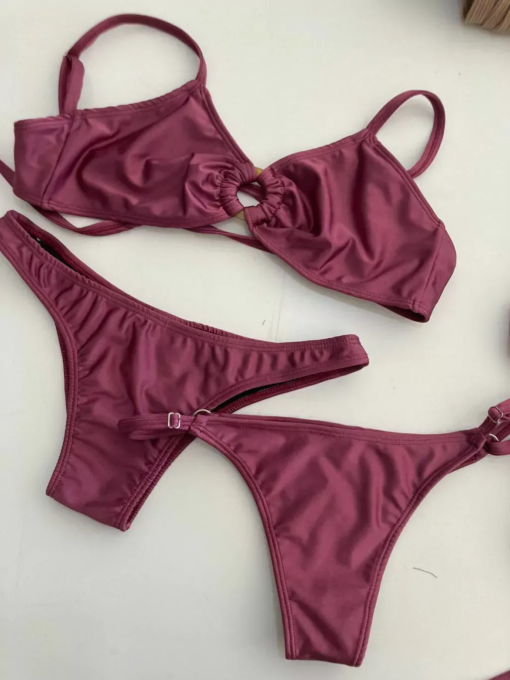 Dos mujeres en bikini posan en una playa de arena bajo un cielo azul.