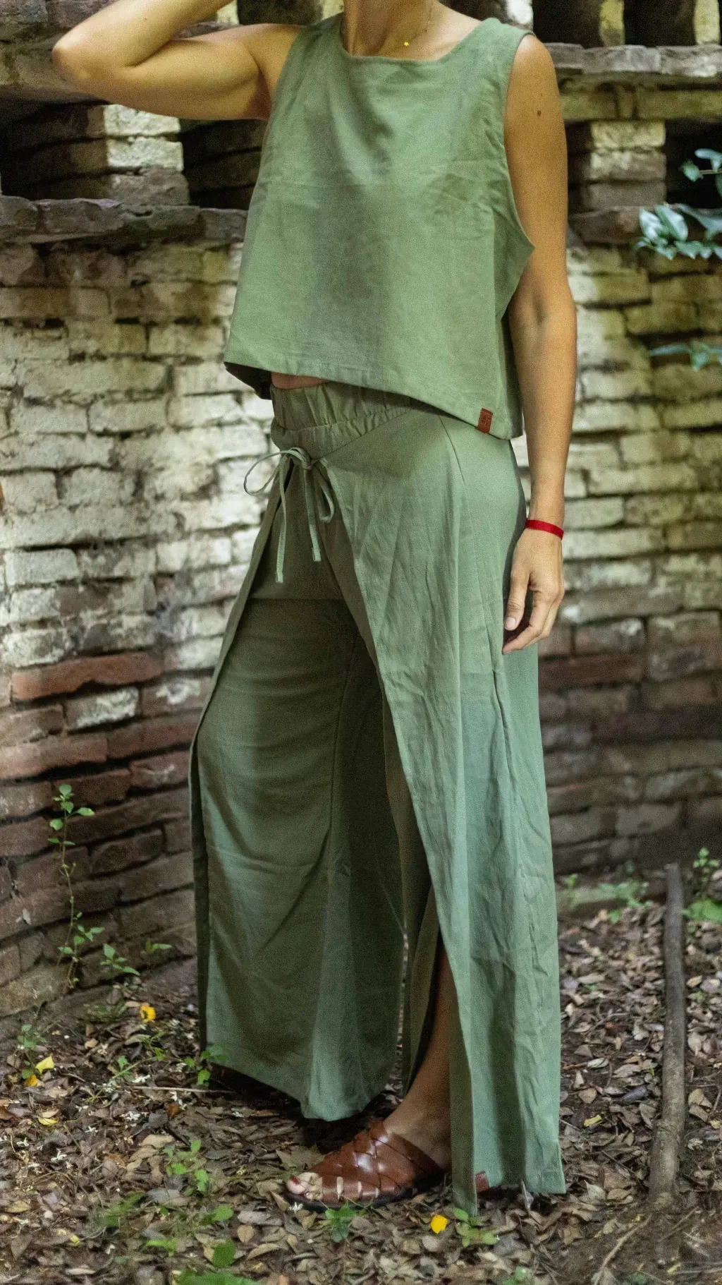 Mujer con una camiseta sin mangas de color rosa claro y pantalones a juego, luciendo un collar y una pulsera.