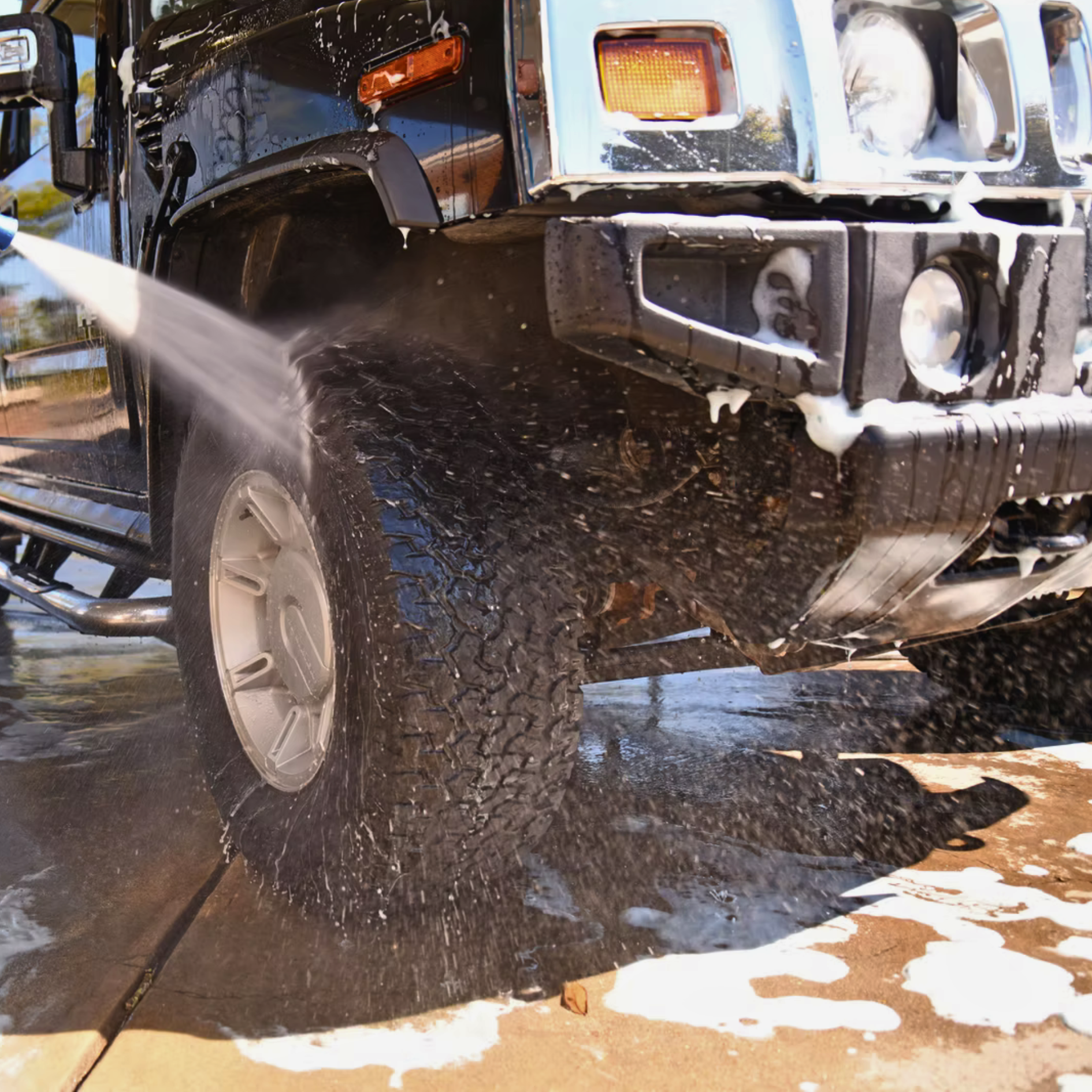 Black Hummer being washed with water, soapy foam on the front.