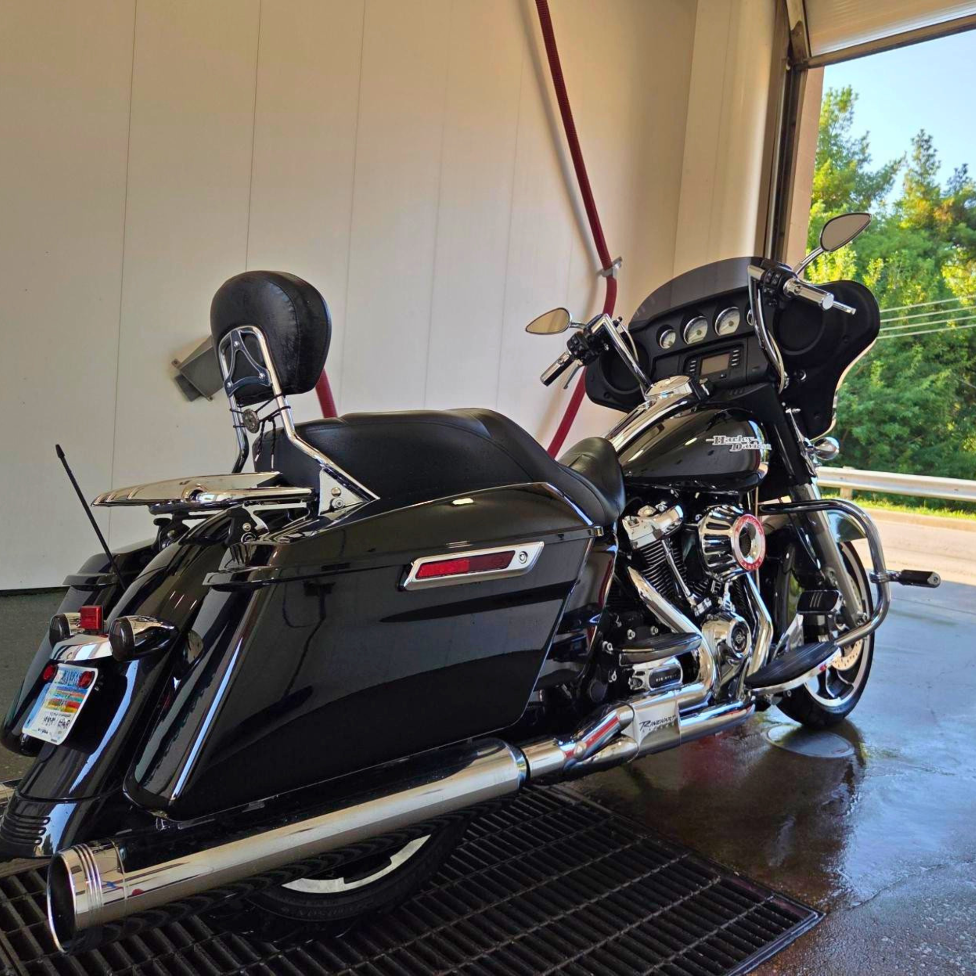 Black touring motorcycle parked indoors on a garage floor, with chrome details and a rear trunk.
