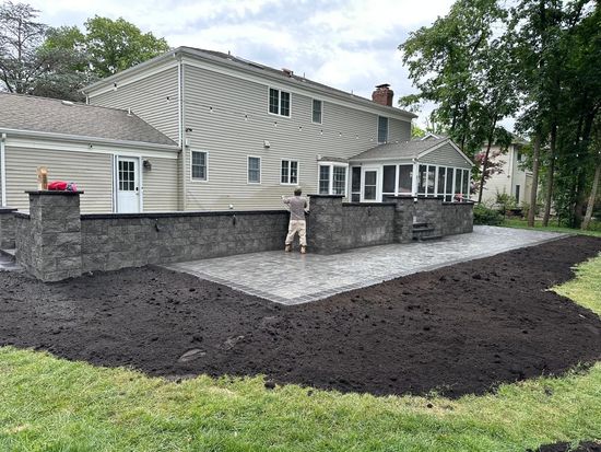 A man is working on a patio in front of a large house.