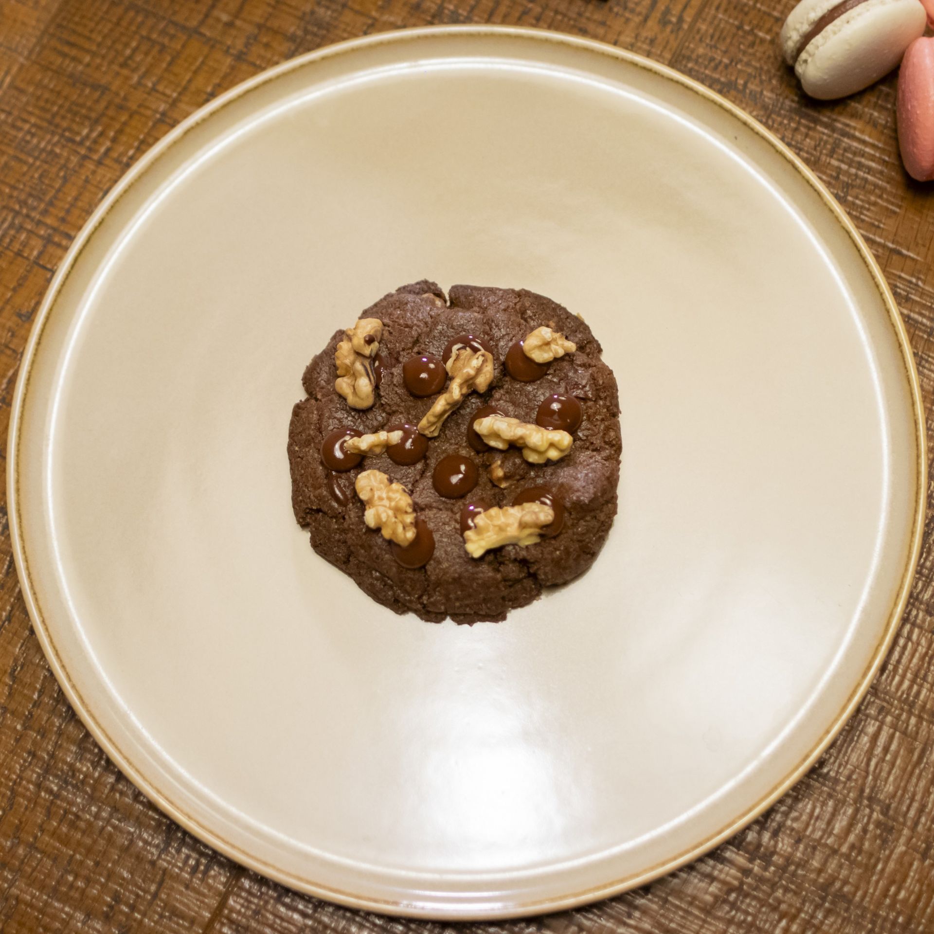 Una galleta de chocolate con nueces y chispas de chocolate en un plato blanco