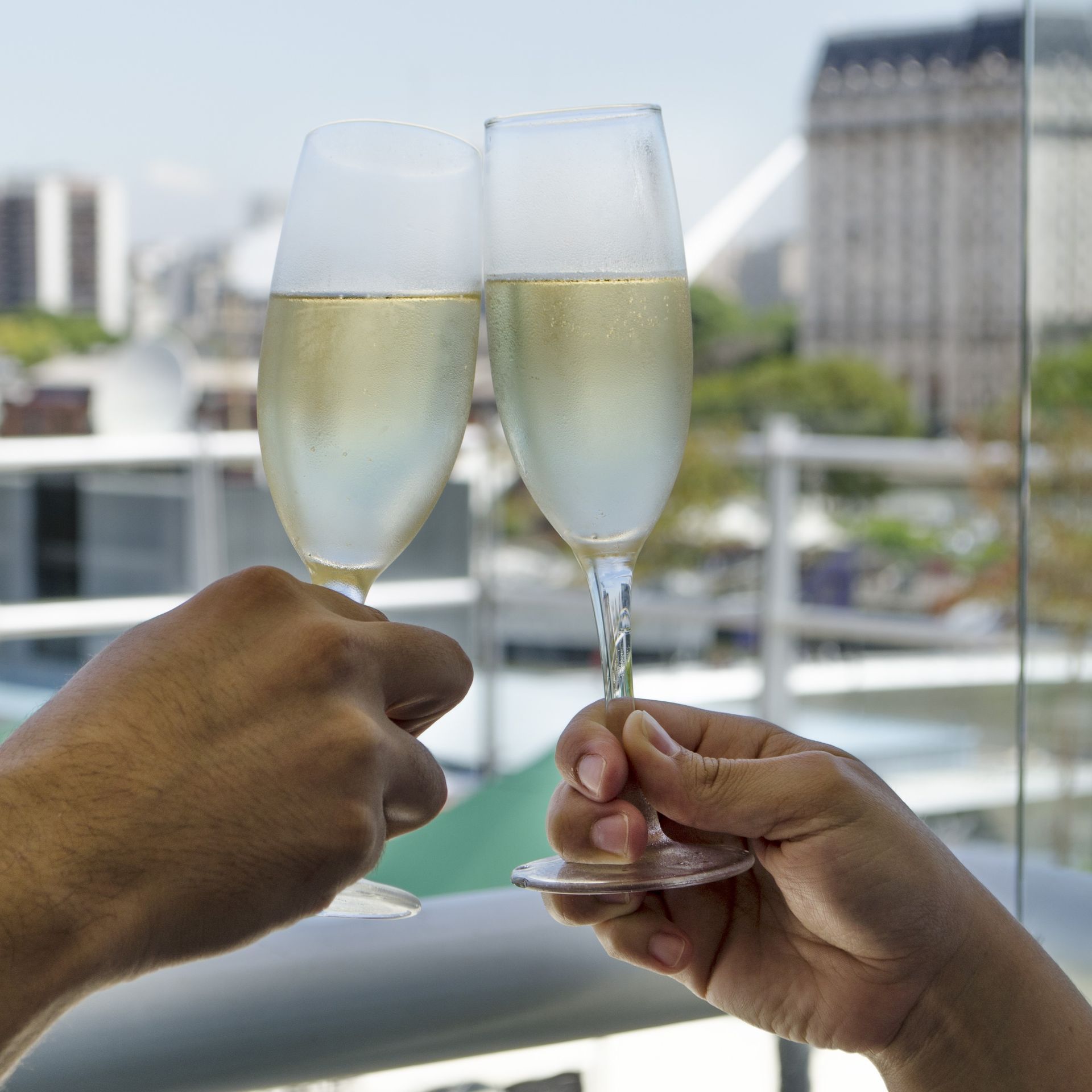 Dos personas brindando con copas de champán frente a una ventana