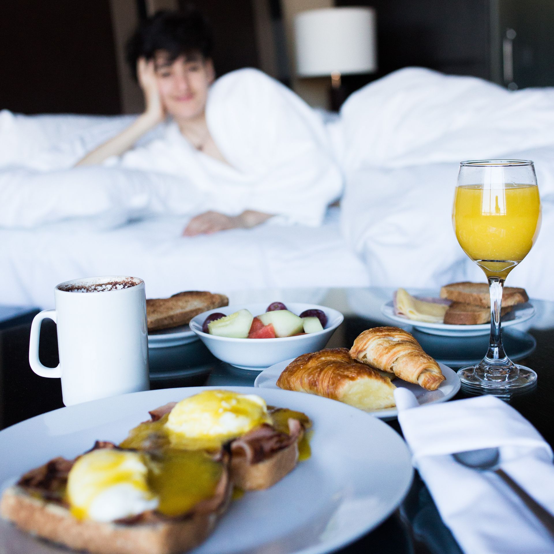 Una mujer está acostada en una cama con un vaso de jugo de naranja.