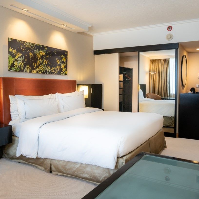 Una habitación de hotel con una cama grande y una mesa de cristal.