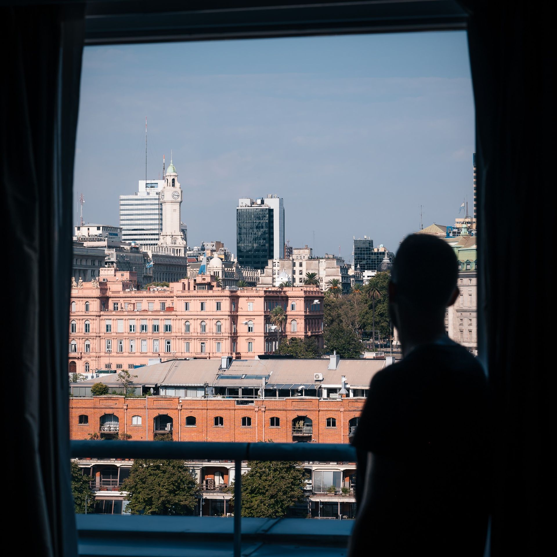 Una persona mirando por una ventana a una ciudad.
