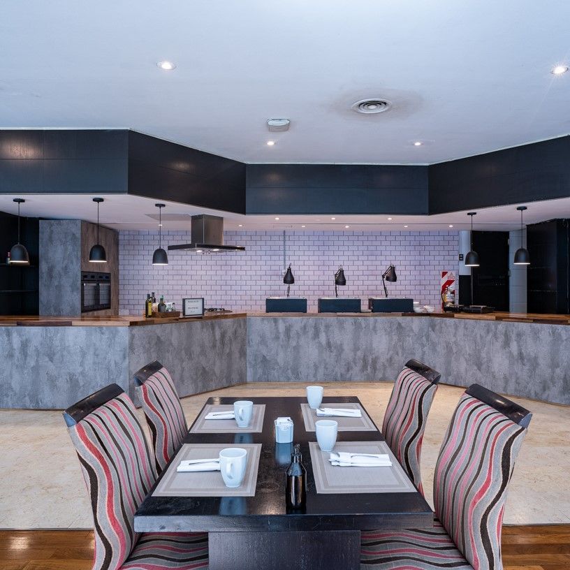 Un comedor con mesa y sillas y la cocina al fondo.