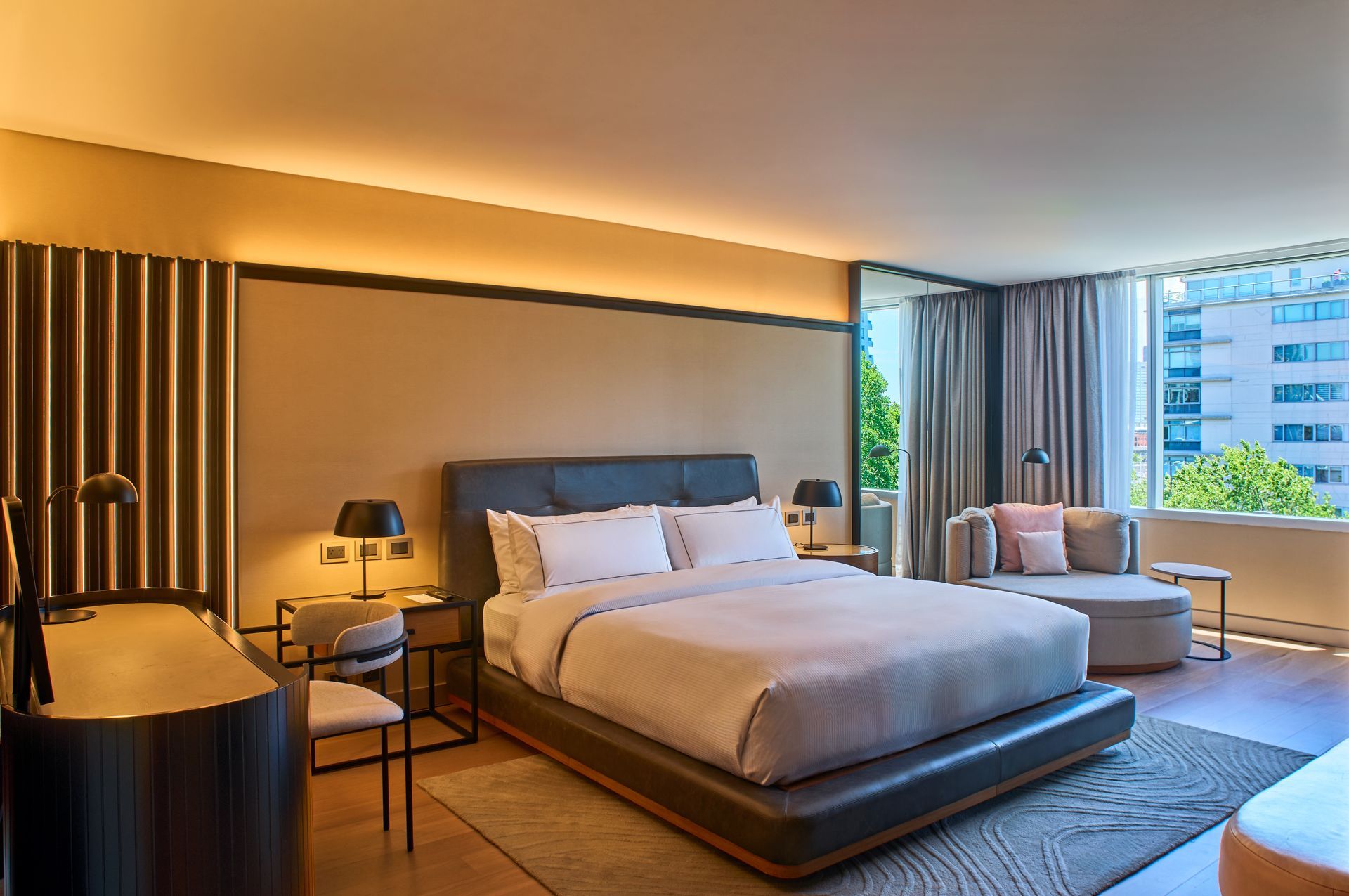 Una habitación de hotel con una cama grande y un banco verde.