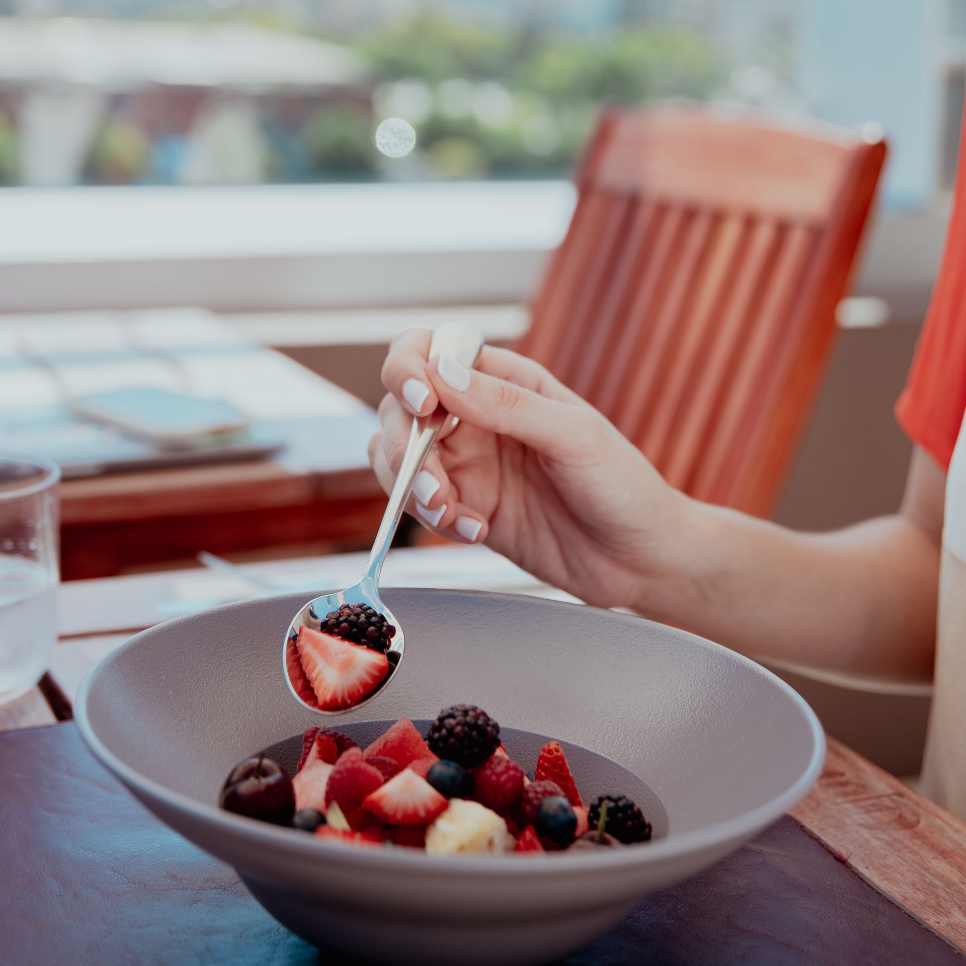 Una persona sostiene una cuchara sobre un plato de fruta.