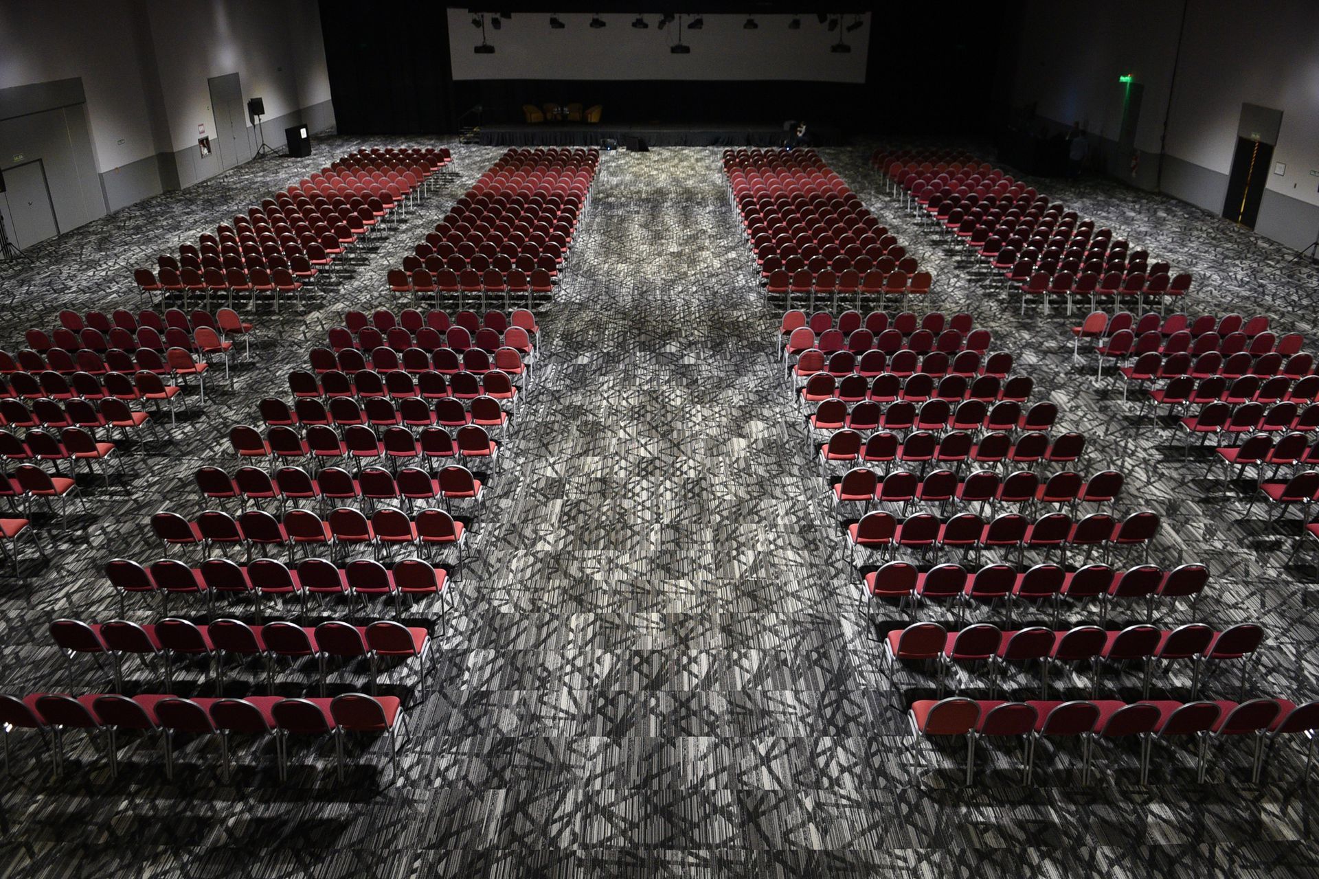 Filas de sillas rojas están alineadas en un gran auditorio.