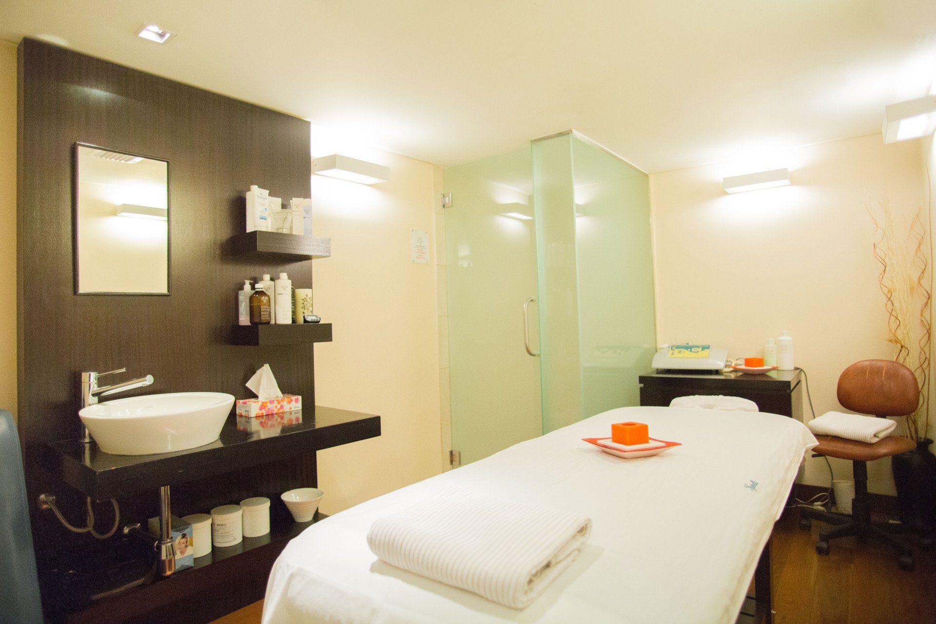 Una camilla de masaje en una habitación con lavabo y espejo.