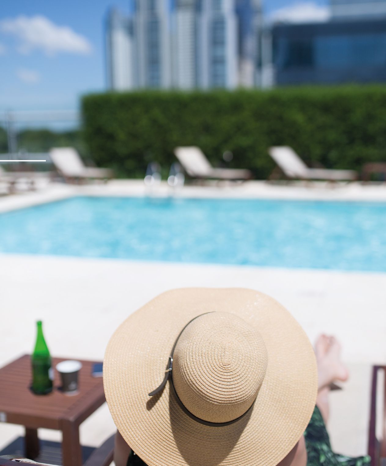 Una mujer con sombrero está sentada junto a una piscina.