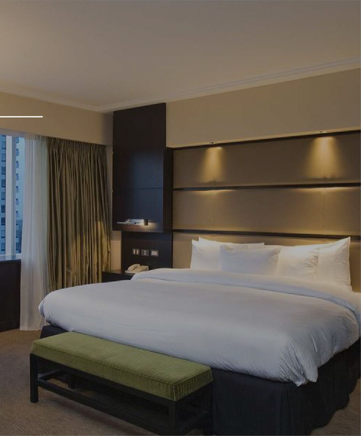 Una habitación de hotel con una cama grande y un banco verde.