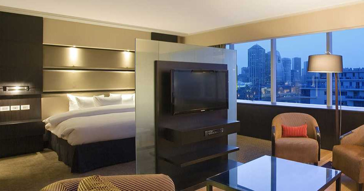 Una habitación de hotel con una cama, televisión, sillas y una mesa.