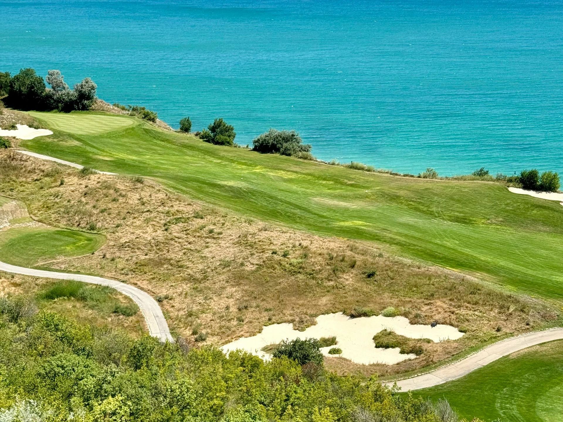 An aerial view of a golf course with the ocean in the background.