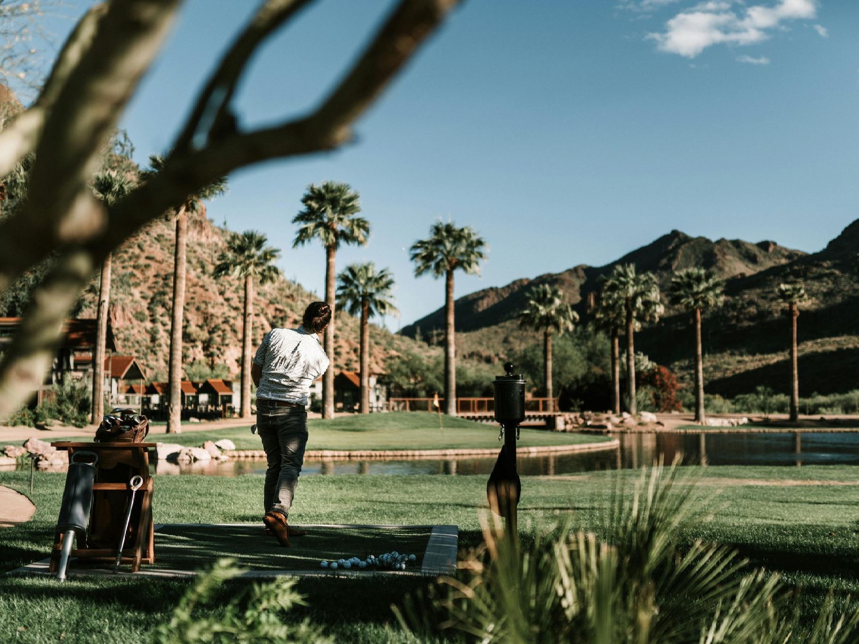 A man is walking in a park with palm trees and mountains in the background.