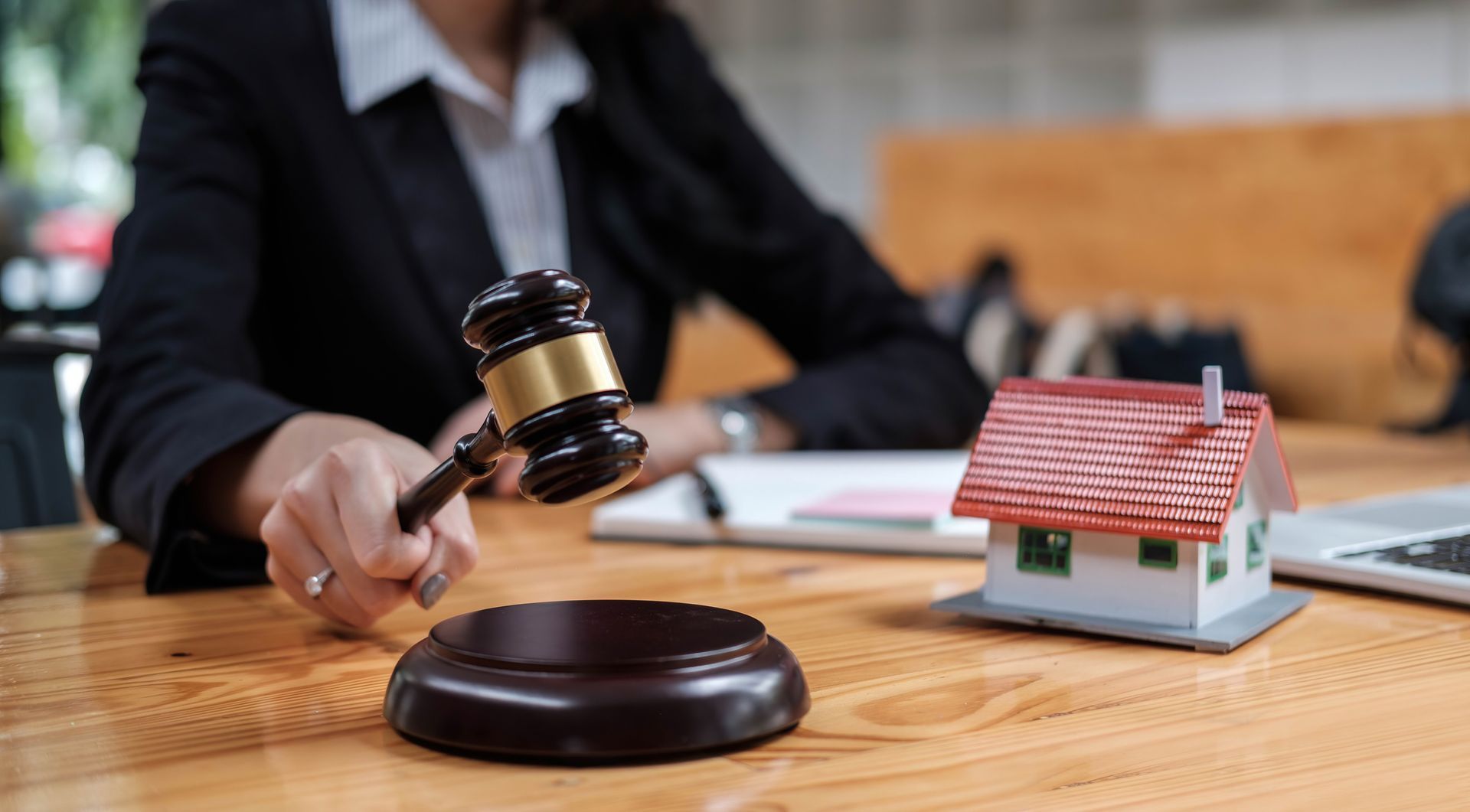 A woman is holding a gavel in front of a model house. A woman is holding a gavel in front of a model house.