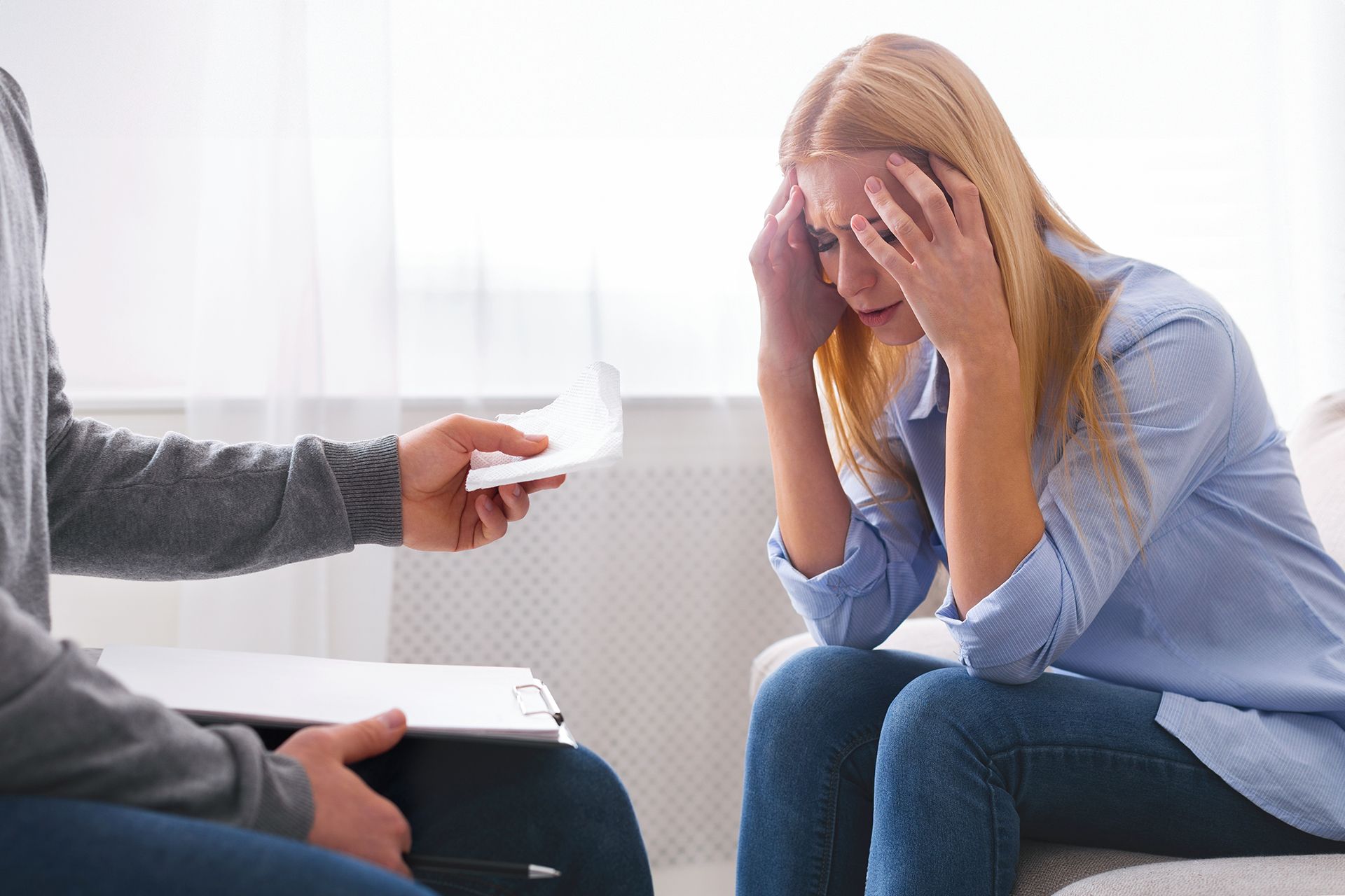 Woman in distress receives documents from someone in a counseling setting.