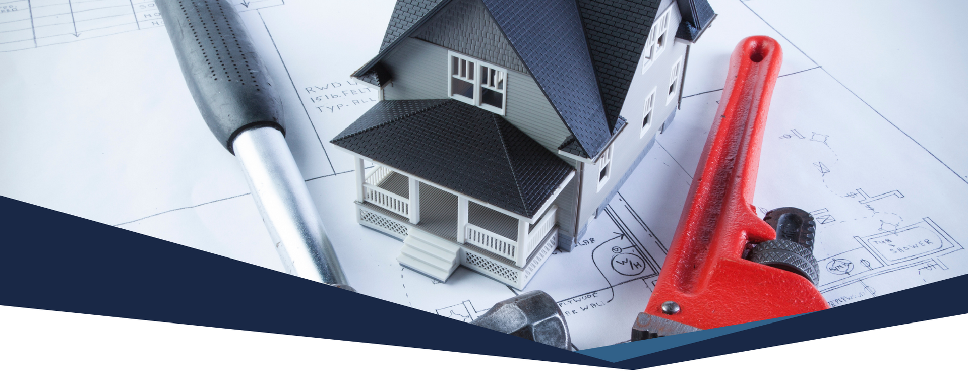 A miniature model house sits on architectural blueprints, flanked by a metal stylus and a red pipe wrench.