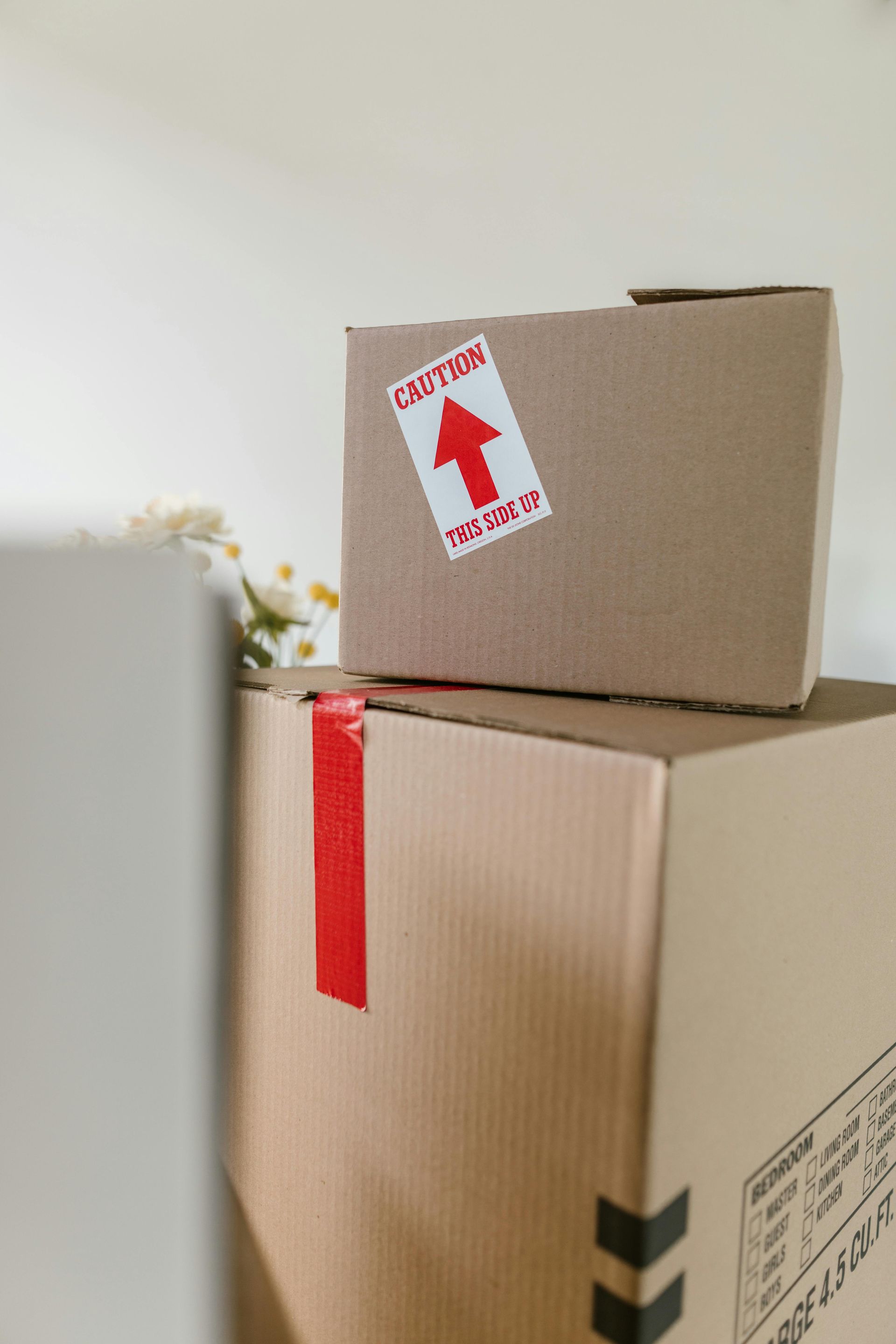A stack of cardboard boxes in a kitchen including one that says ' vibes ' on it