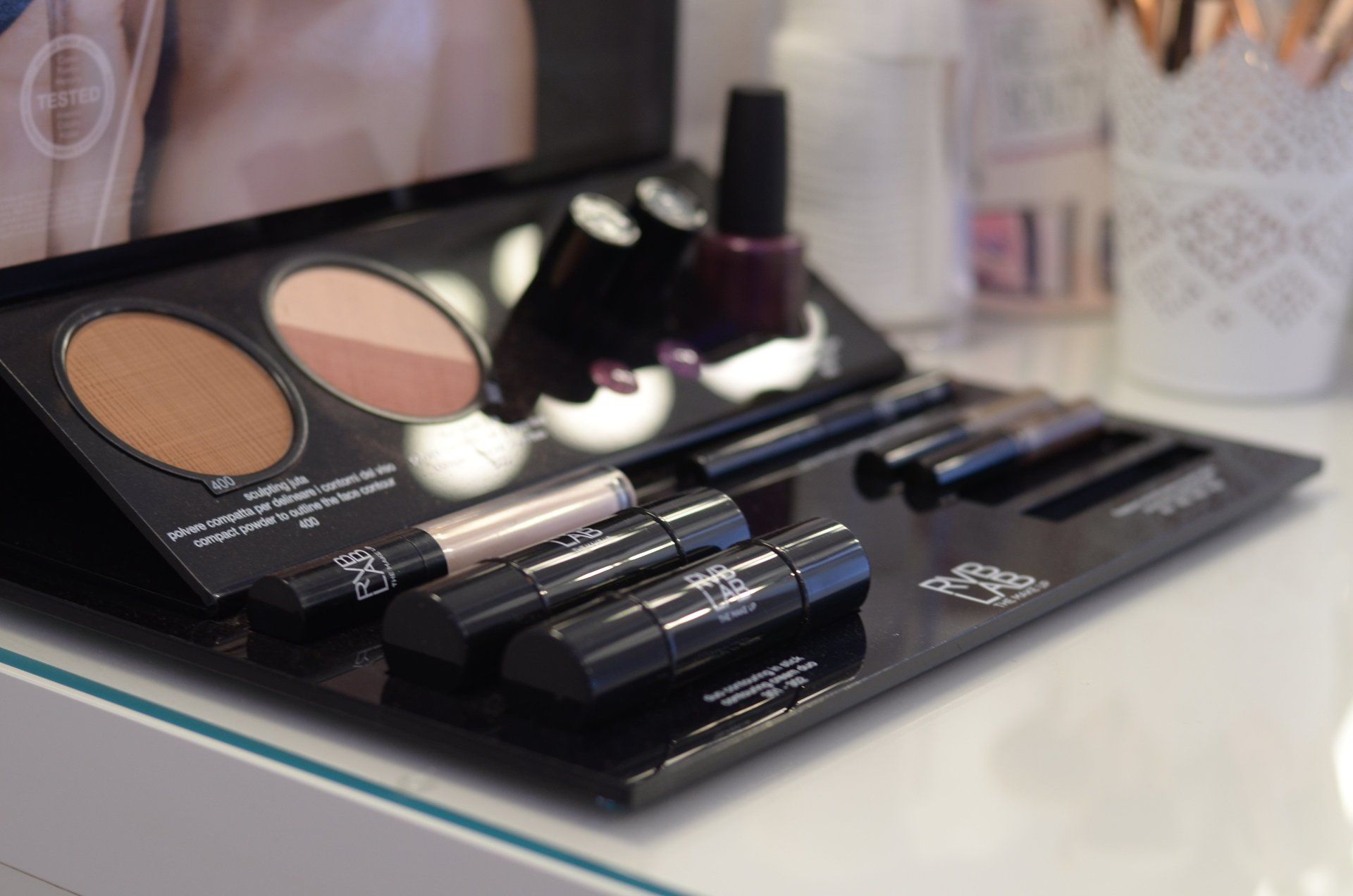 Auf einem Tisch steht eine Make-up-Palette neben einer Flasche Nagellack.