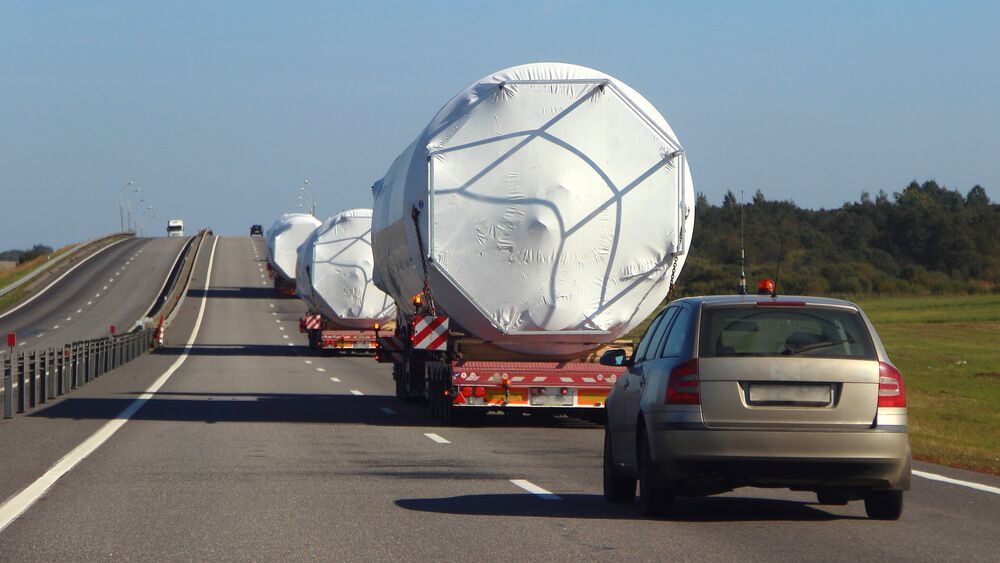 A Car is Driving Down a Highway Next to a Truck Carrying Large Containers — ASAP Towing Pty Ltd in Widgee, QLD