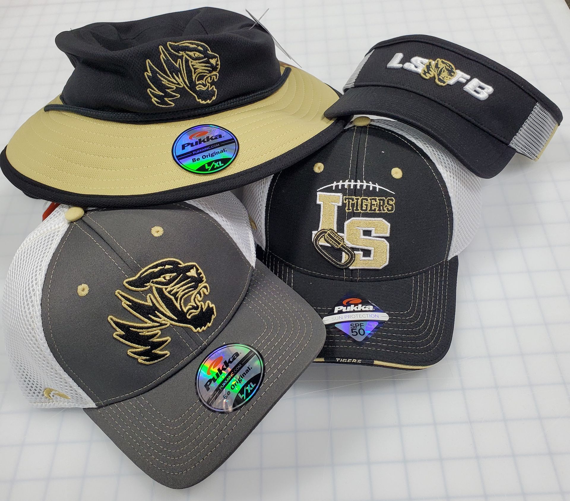Four LS hats with logos and visors on a white surface.
