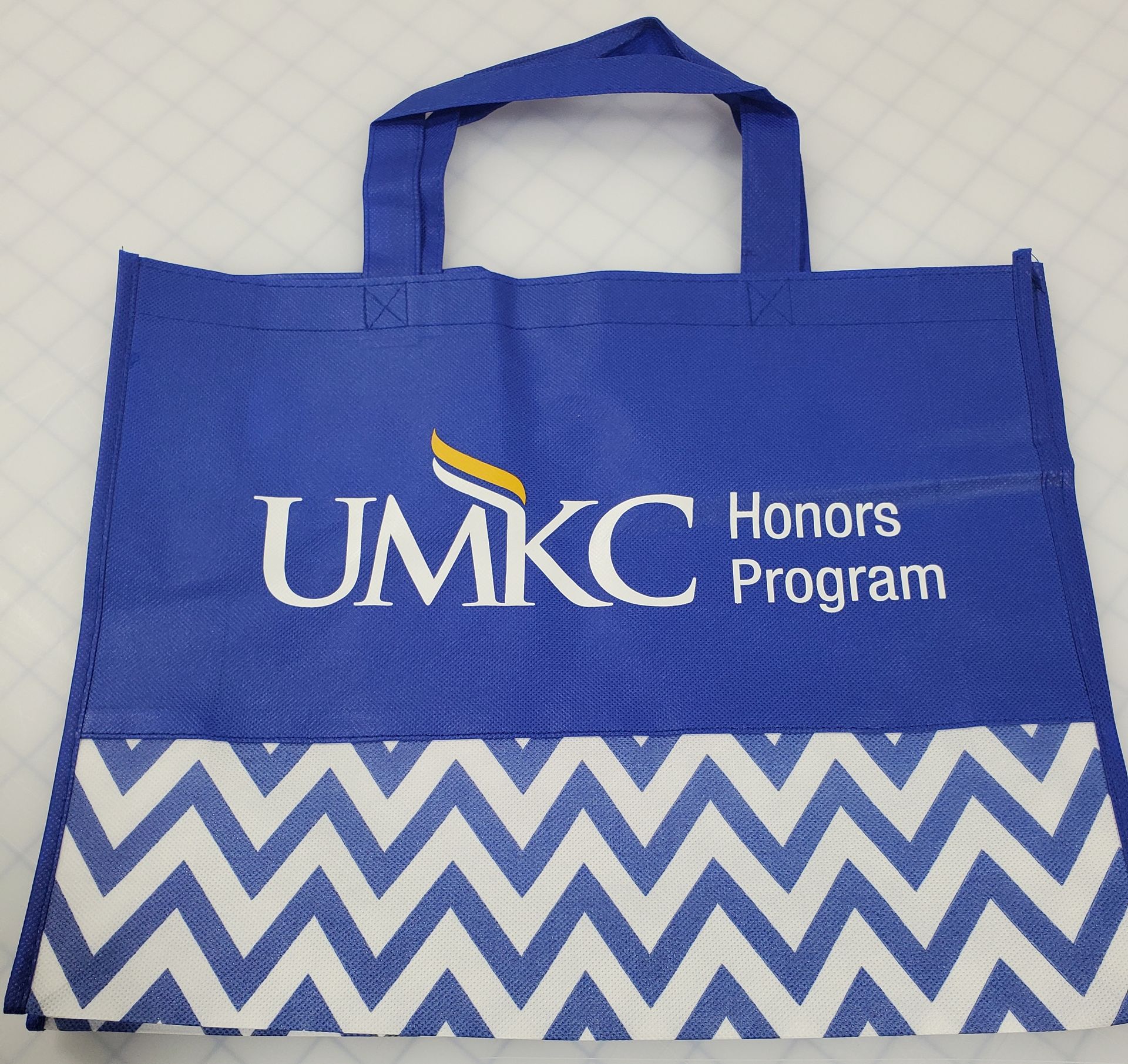Blue UMKC Honors Program tote bag with white chevron bottom.