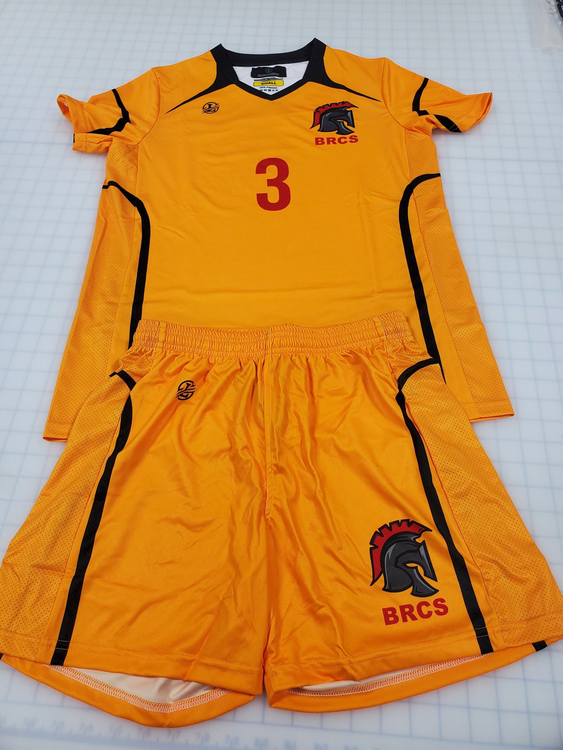 Orange athletic uniform with number 3 and a spartan logo, laid flat.