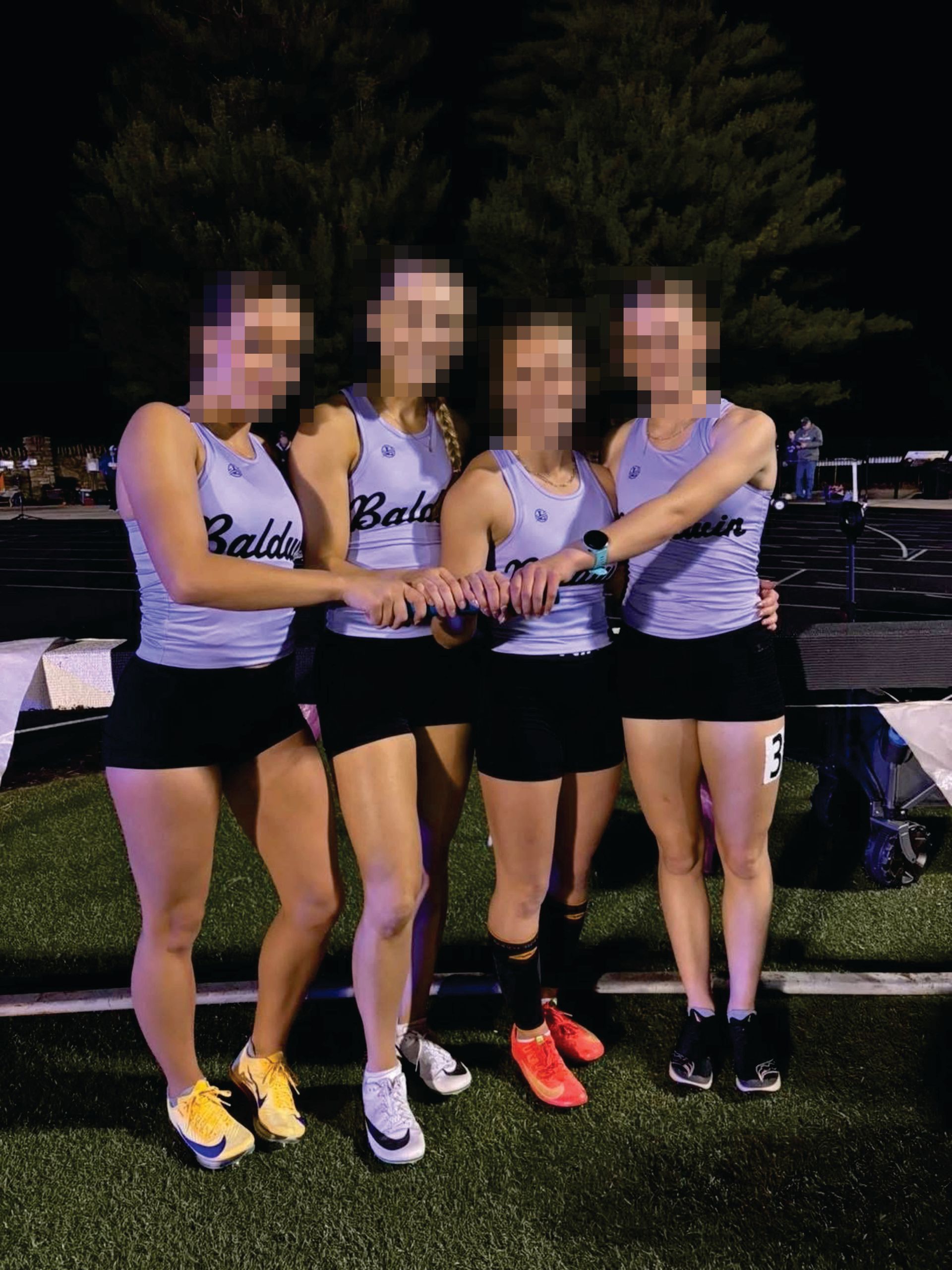Four athletes in light purple jerseys and black shorts stand in a line on a track, holding their batons together.