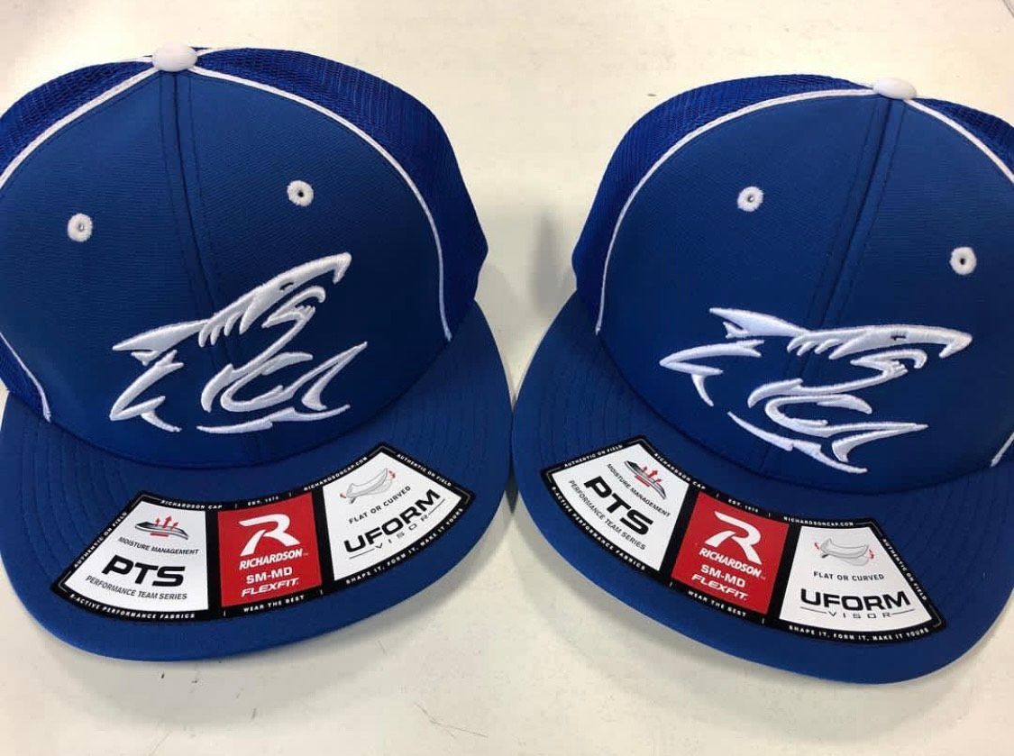 Two blue baseball caps with white shark logo and brand labels.