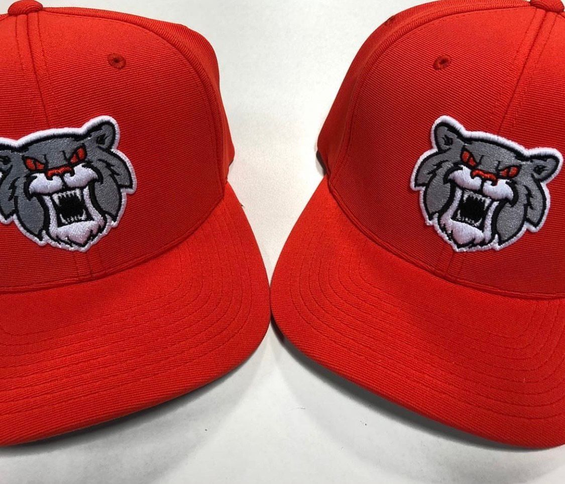 Two red baseball caps with a gray and white snarling wolf logo.