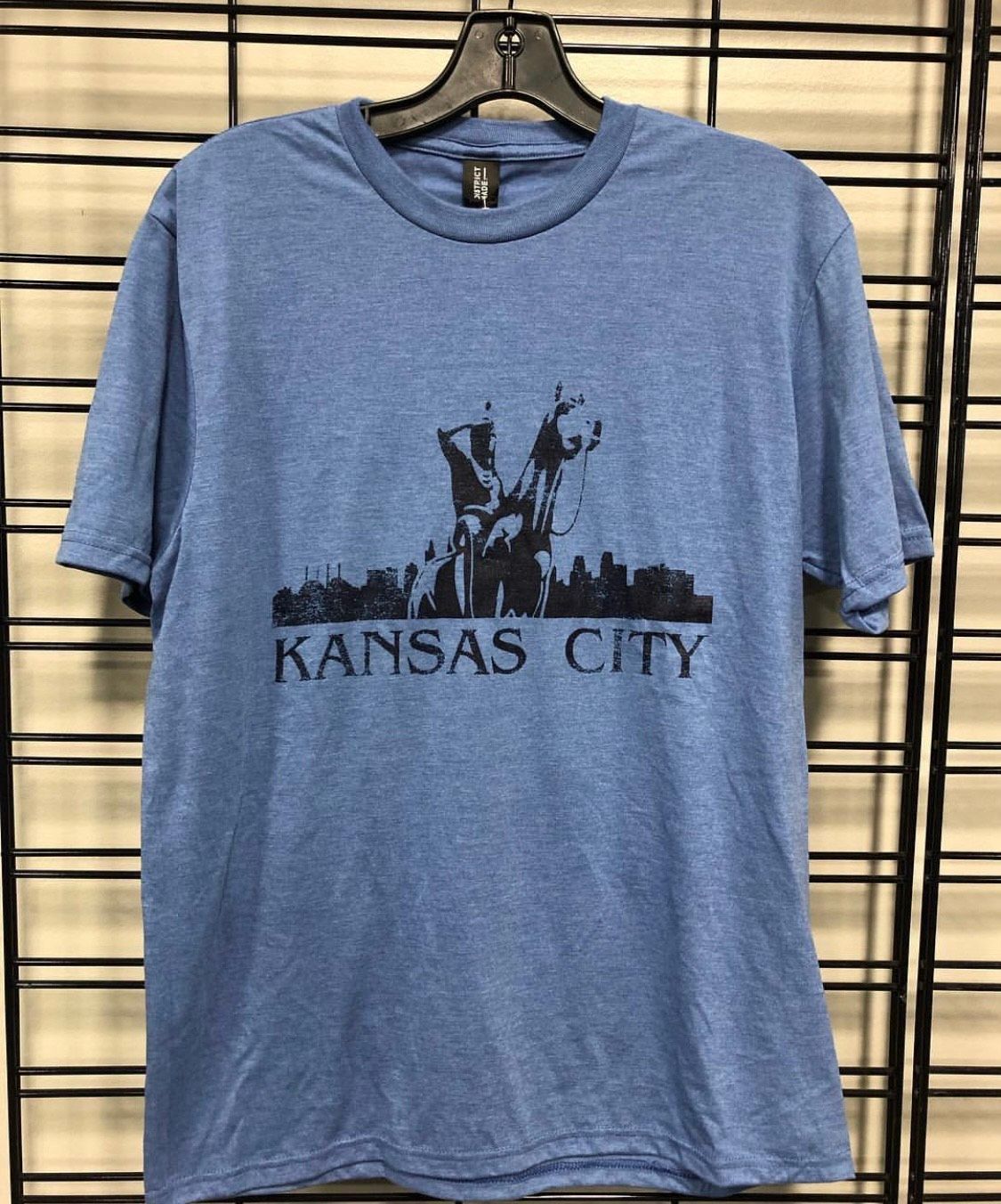 Blue t-shirt with a black silhouette of the Kansas City skyline, including a statue, and the words 