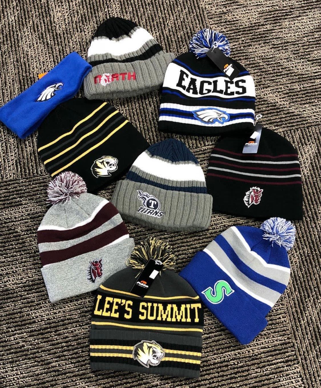 Various winter hats with school/team logos. Includes beanies and a headband, with pom-poms and logos.