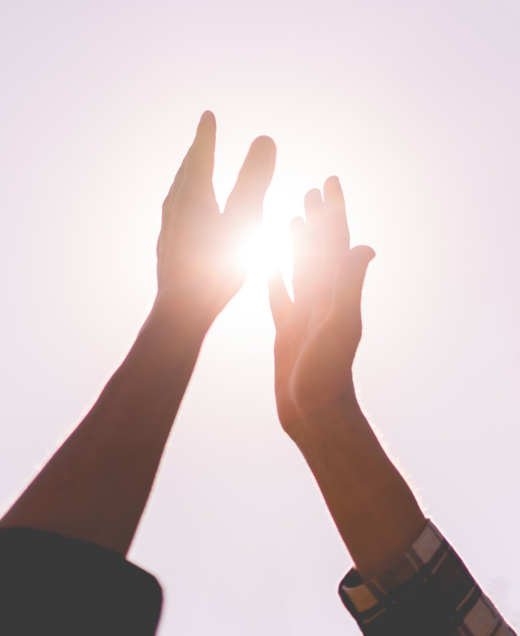 Zwei Hände strecken in den Himmel und umfassen die Sonne