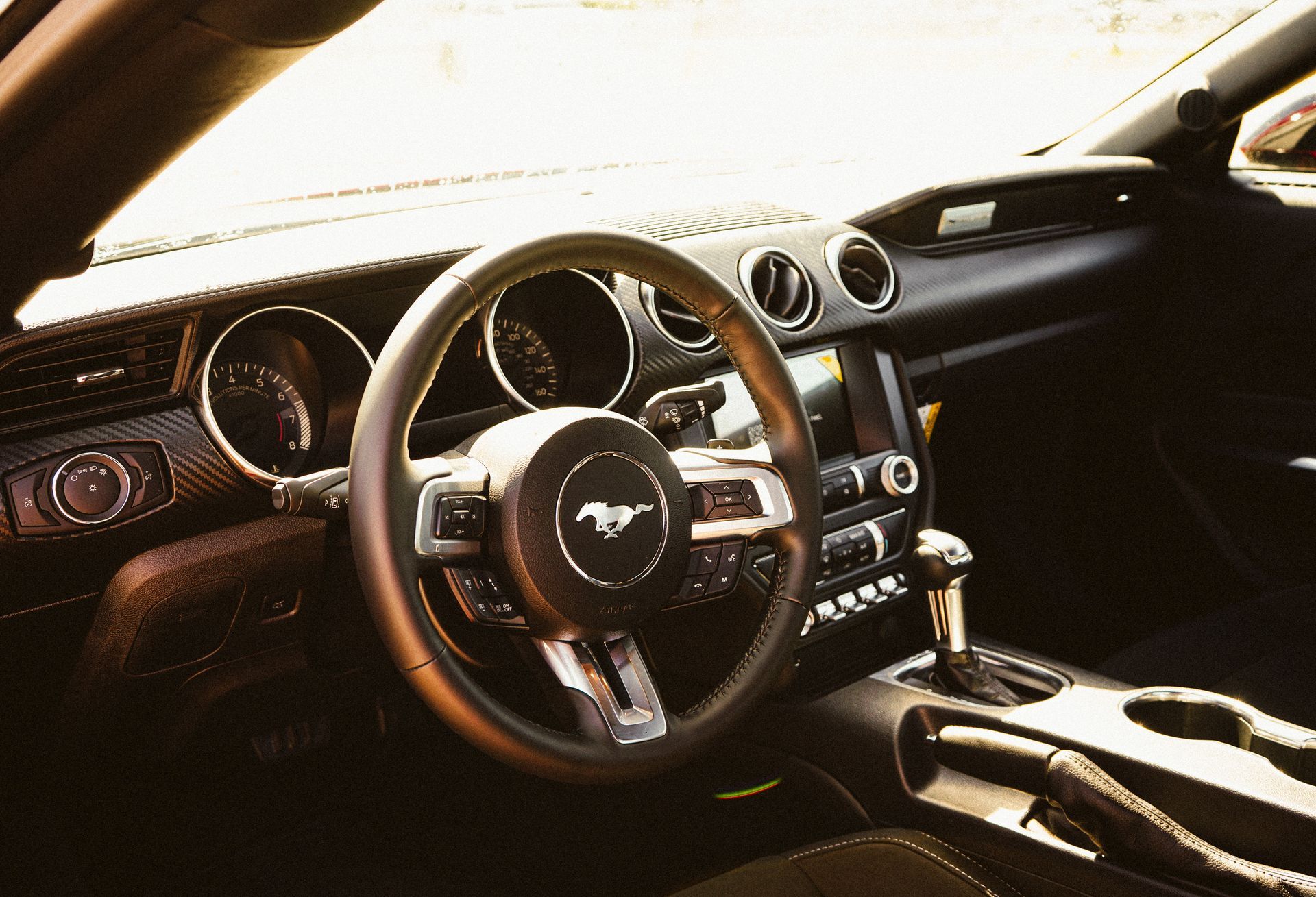 Interior view of a black Ford Mustang dashboard, steering wheel, and console.