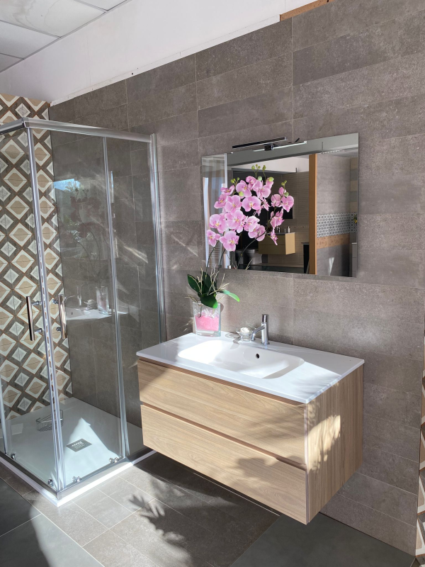 Bagno moderno con doccia, lavabo e specchio, decorato con fiori rosa.